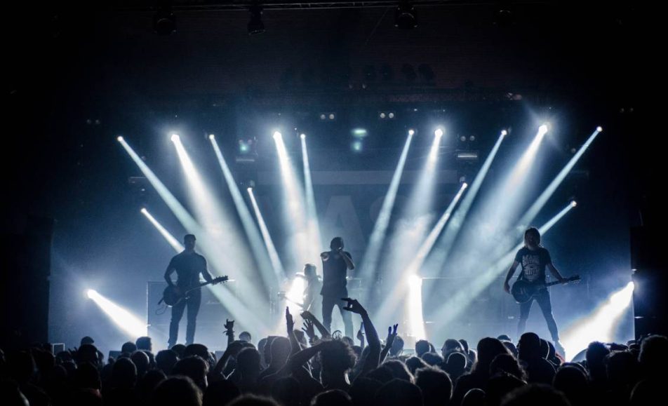 pohled na pódium z hlediště na hrající rockovou kapelu