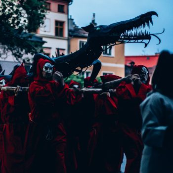 lidé nesou kovového draka