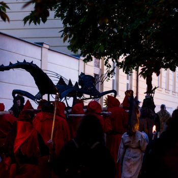 lidé nesou kovového draka