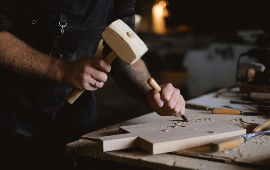 muž tesá dlátem do dřeva