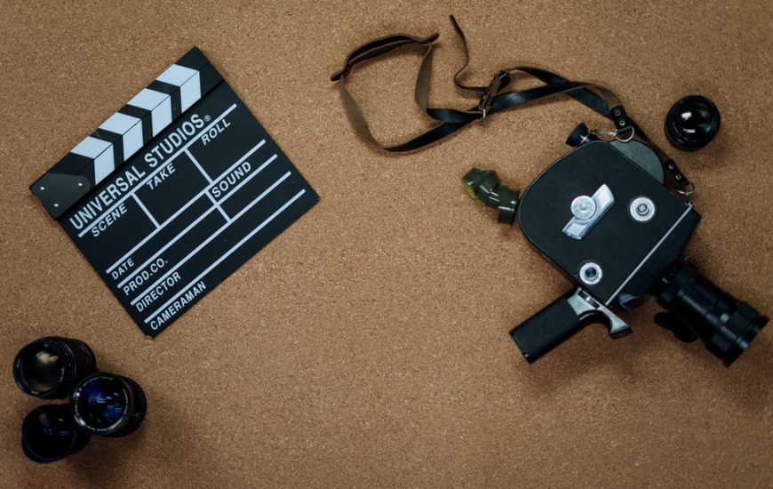 kamera s objektivy a klapkou položené na korkovém koberci
