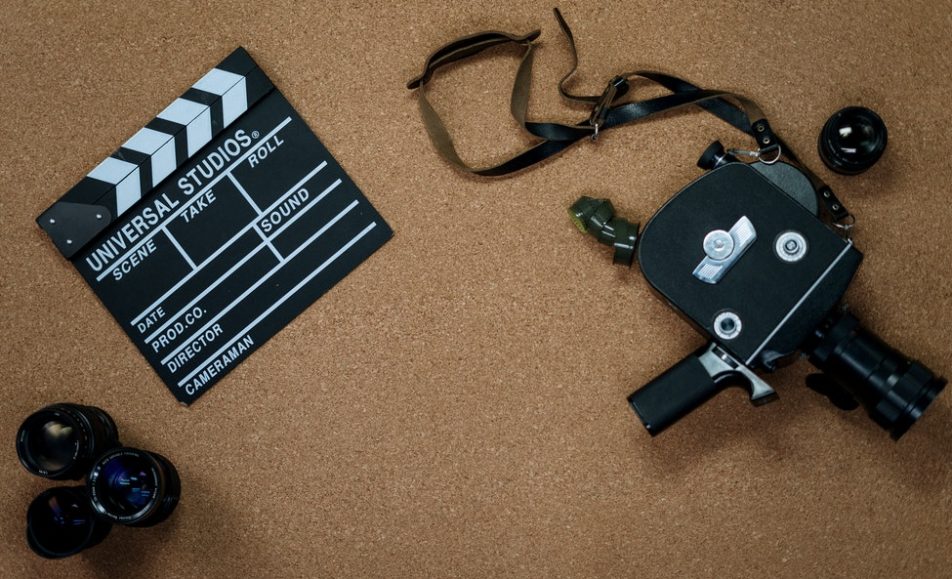 kamera s objektivy a klapkou položené na korkovém koberci