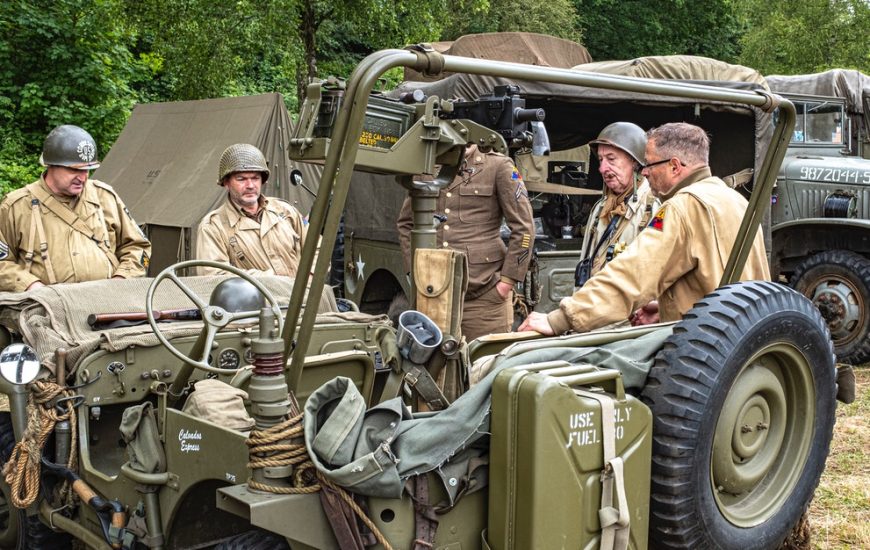 veteráni u jeepu v pozadí stany a vojenská auta