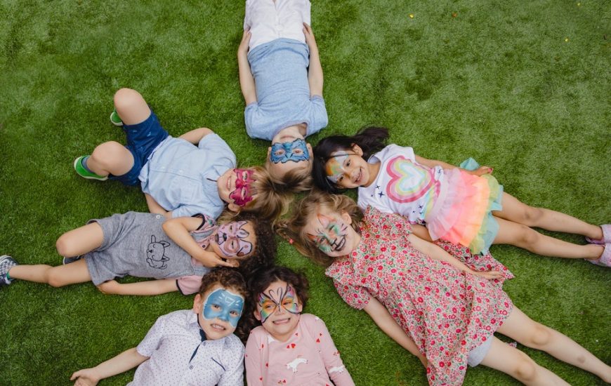 děti leží na trávě hlavami k sobě