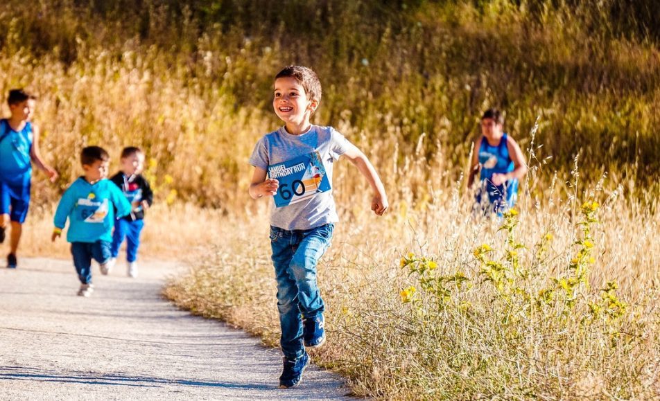děti běží po asfaltové cestě a v okolí je tráva