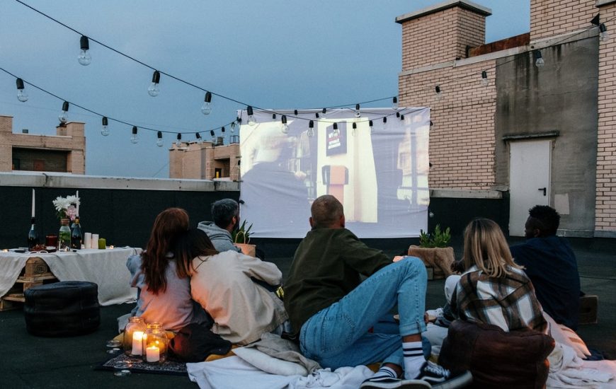lidé venku společně koukají na film na plátně