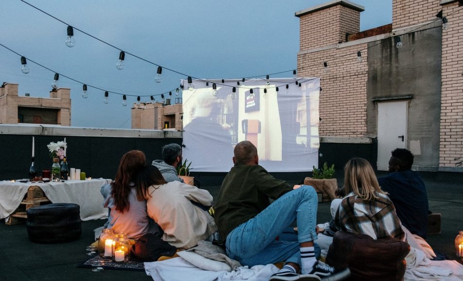 lidé venku společně koukají na film na plátně