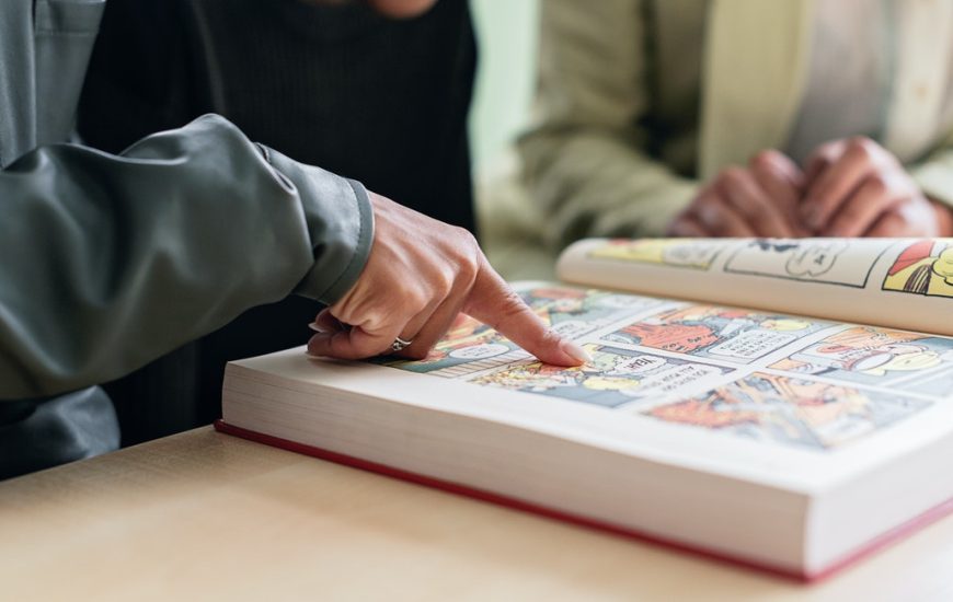 listování komiksovou knihou, kde prst ukazuje na obrázek v ní