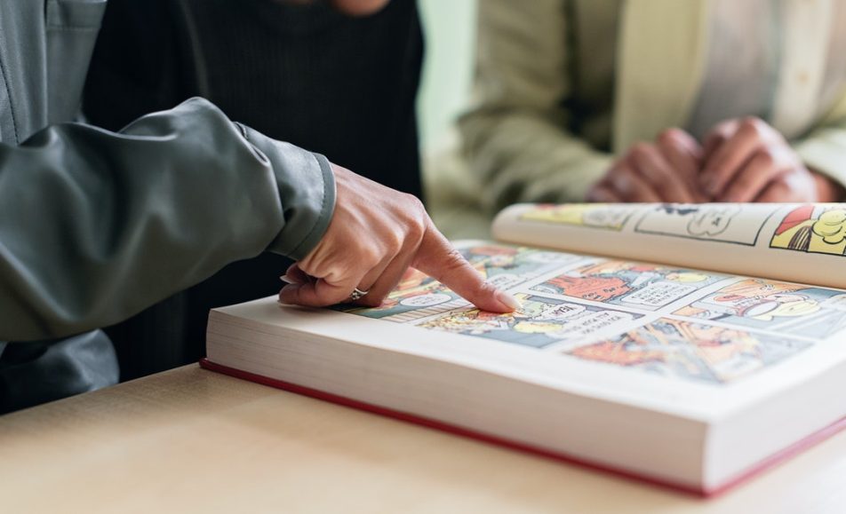 listování komiksovou knihou, kde prst ukazuje na obrázek v ní