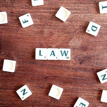 Scrabble kostičky položené na stole, ze kterých je složen nápis LAW.