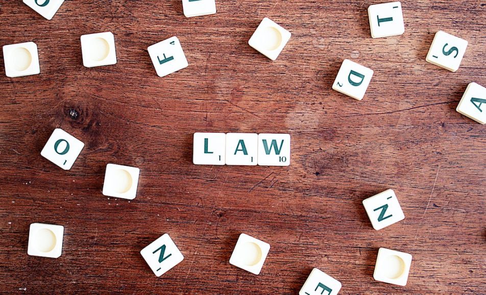 Scrabble kostičky položené na stole, ze kterých je složen nápis LAW.