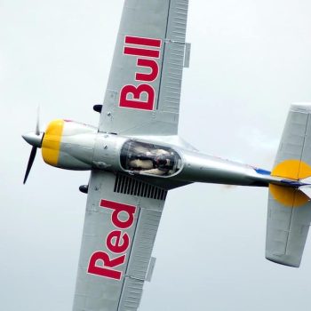 Letící akrobatické letadlo s nápisem Red Bull na křídlech