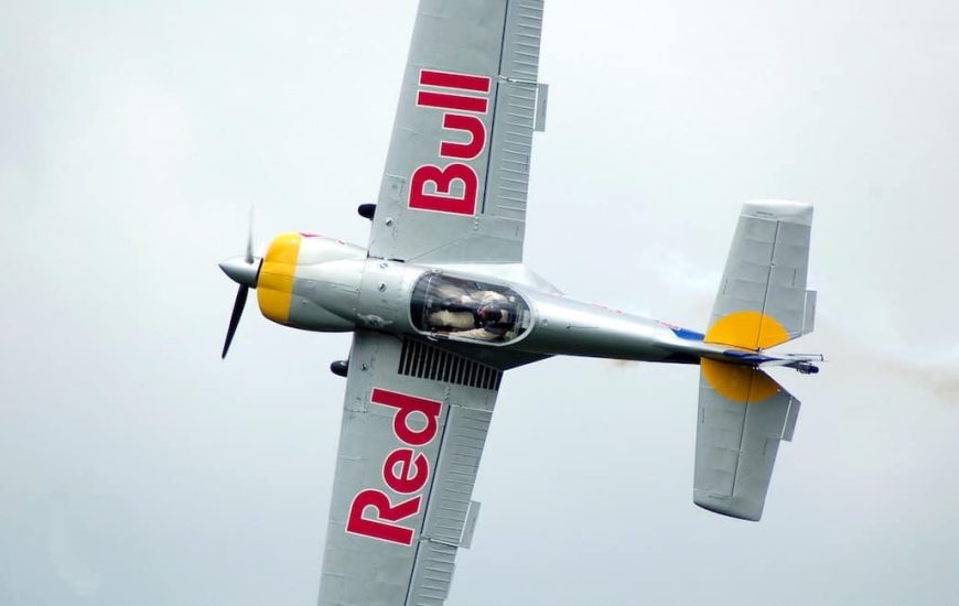 Letící akrobatické letadlo s nápisem Red Bull na křídlech