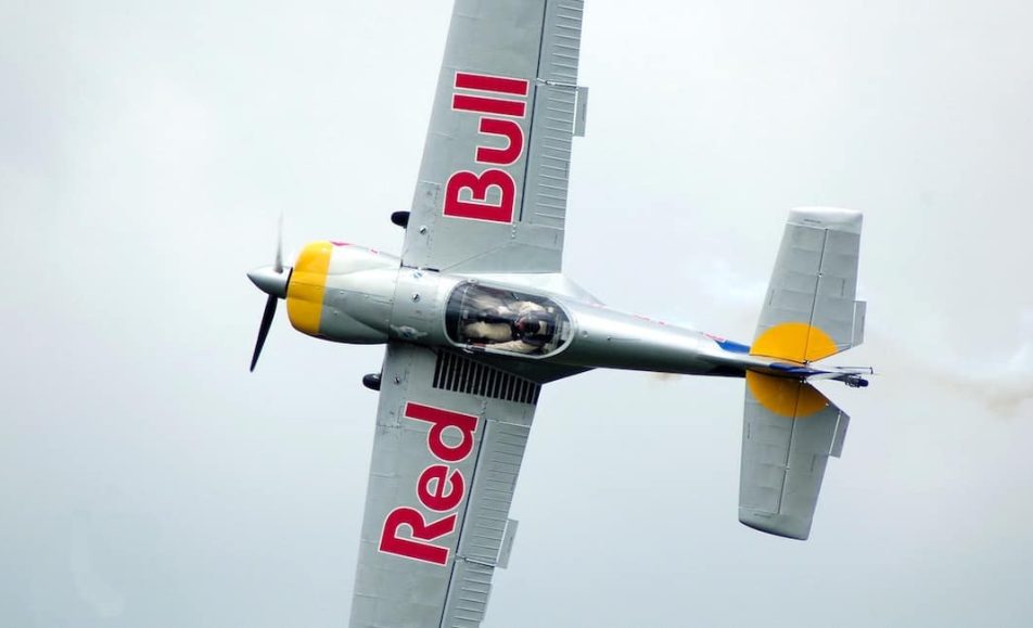Letící akrobatické letadlo s nápisem Red Bull na křídlech