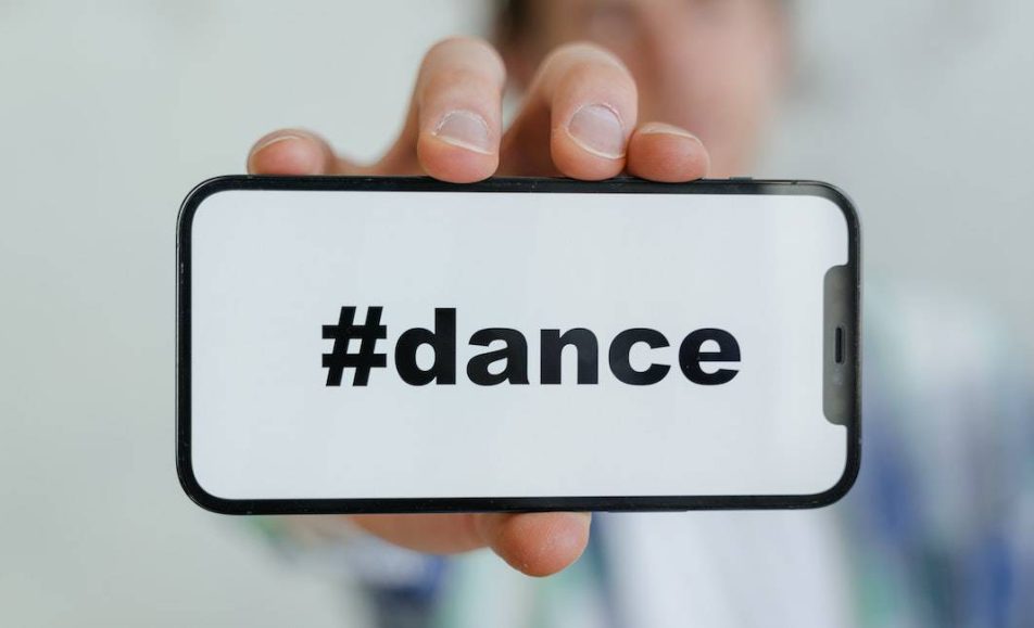 muž drží telefon na němž je nápis #dance